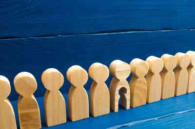 Holzfiguren in einer Reihe, eine hat ein ausgeschnittenes Kind - © Andrii Yalanskyi - stock.adobe.com