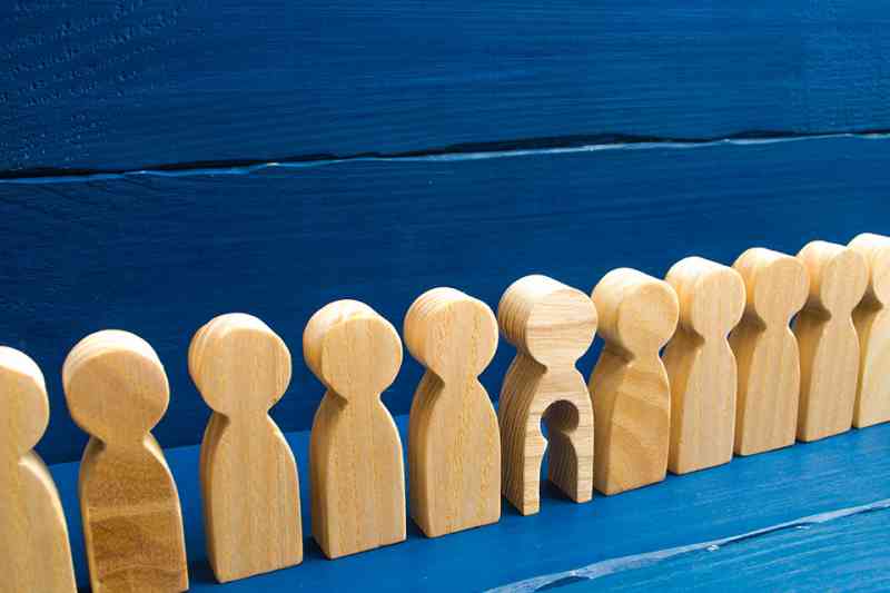 Holzfiguren in einer Reihe, eine hat ein ausgeschnittenes Kind